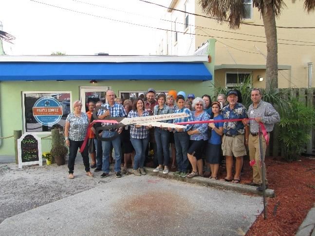 Photo of a group of people cutting a ribbon on a new business.