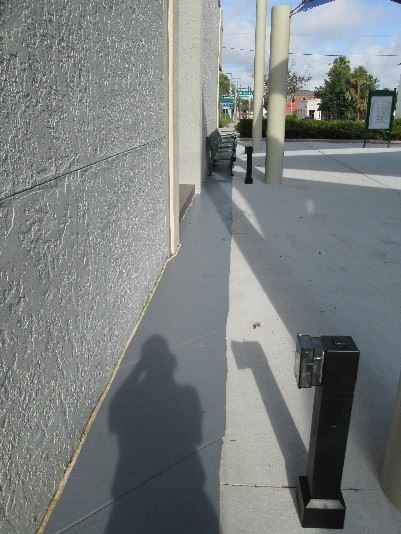 Photo showing an outside electrical outlet on a small stanchion in a courtyard.