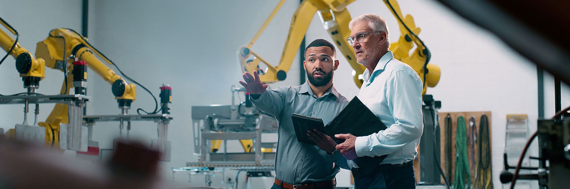 workers pointing at robotic arms