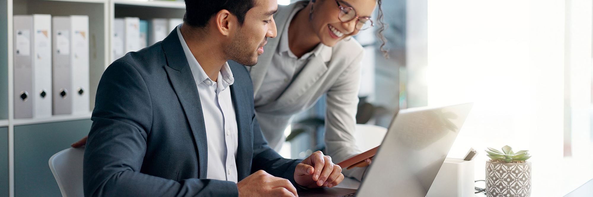 smiling businesspeople looking at computer screen